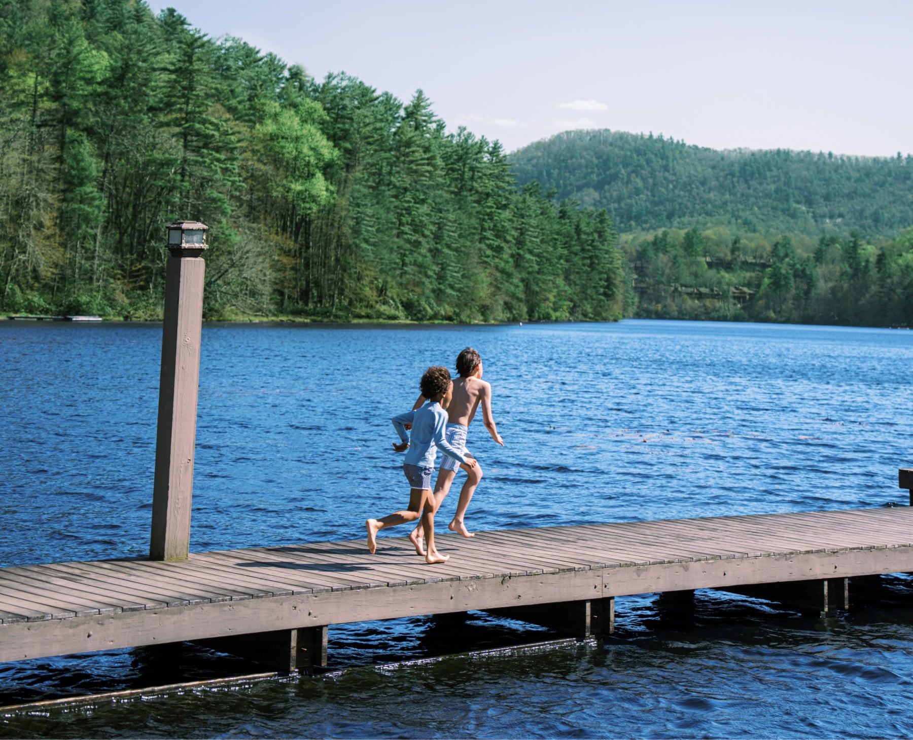 boys wearing minnow running on dock at lake