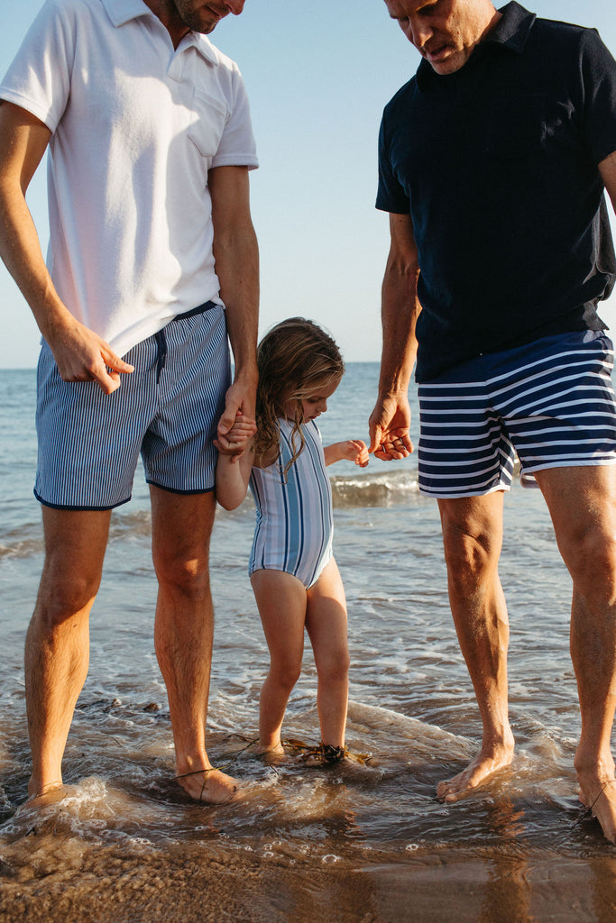 two dads wearing minnow on the beach with their daughter