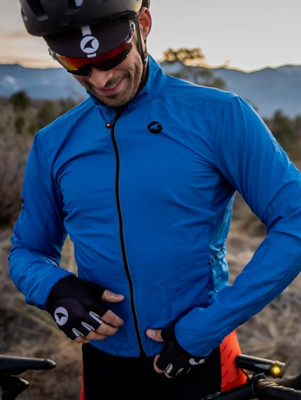 Cyclist putting on a blue Divide Wind Jacket