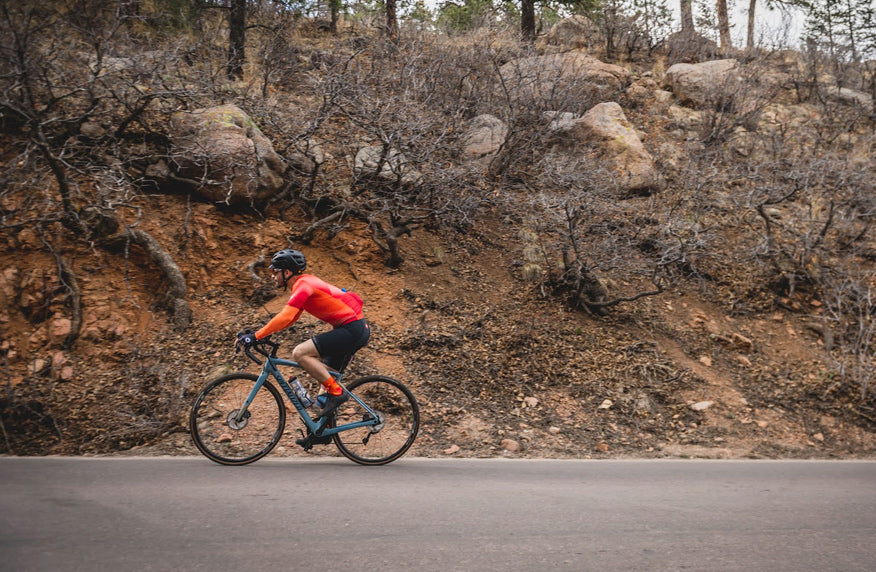 Cyclist on mountainous road wearing a bright colored Summit Aero Mesh Jersey