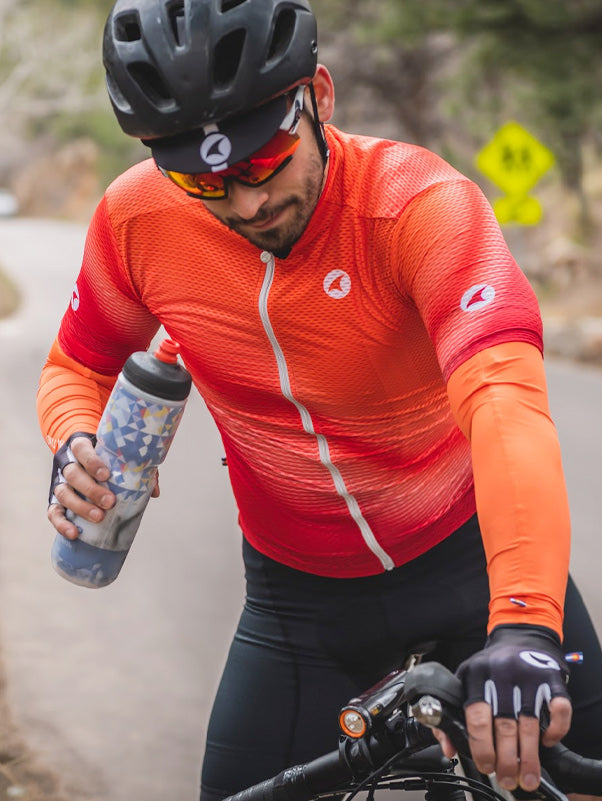 Cyclist stopping to take a drink from a water bottle, wearing the Summit Aero Mesh Jersey and matching Summer Sleeves