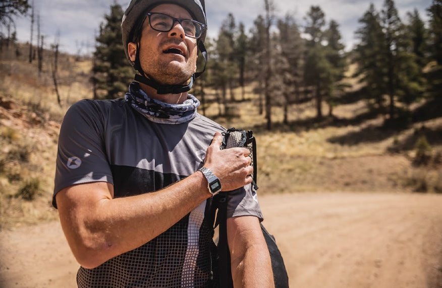 Cyclist taking off his backpack, gravel road in the background