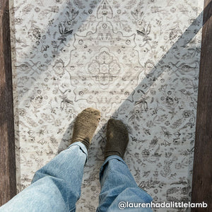 Emile latte neutral floral print standing mat shown looking down on a womans feet standing on the mat and sun beams casting shadows over the mat