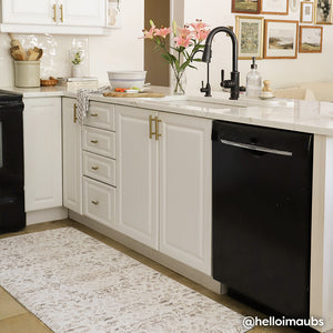 Emile latte neutral floral print standing mat shown in white kitchen in front of the sink in size 30x108