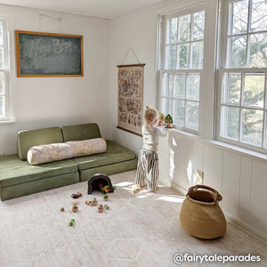 Ula sienna pink boho print play mat shown in play room with blocks scattered on the play mat and little girl playing with toys on the windowsill. @fairytaleparades written in bottom right hand corner.