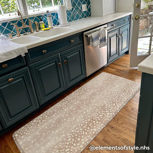 Fawn brown neutral animal print standing mat shown in dark teal kitchen with in size 30x108. @elementsofstyle.nhs written in the lower right hand corner.