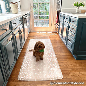 Fawn brown neutral animal print standing mat shown in dark teal kitchen with brown doodle dog sitting on the mat. Shown in size 30x108. @elementsofstyle.nhs written in the lower right hand corner.