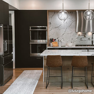 Fawn silver gray animal print standing mat shown modern black and gray kitchen. @lutzgohome written in the lower right hand corner.