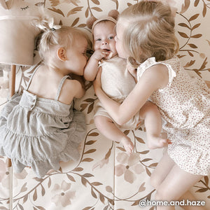 Faye Toffee neutral floral tumbling mat with 2 sisters and baby brother laying on the mat 