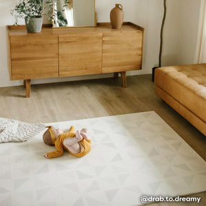 Gallery terrazzo cream geometric print play mat shown in bedroom with baby girl laying on her back. @drab.to.dreamy written in bottom right hand corner. 