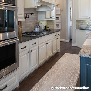 Fawn brown neutral animal print standing mat shown in white and gray kitchen. Shown in size 30x108. @thehouseofemmaline written in the lower right hand corner.