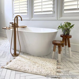 Arden pearl cream and beige ornate print bath mat shown in bathroom in front of standalone bathtub vanity in size 21x34