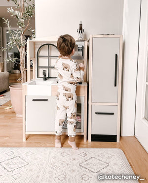 Nama Standing Mat in Ula Oat neutral boho print. Anti-fatigue kitchen mat shown in play room with toddler playing with a childrens kitchen set.