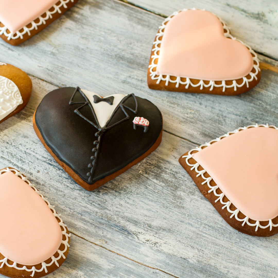 Heart shaped cookies decorated in pink and groom tux with icing