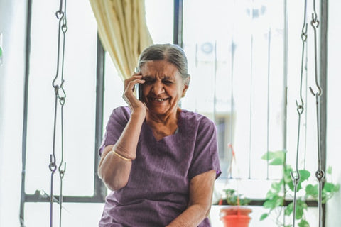 woman in purple V-neck top smiling while on the phone
