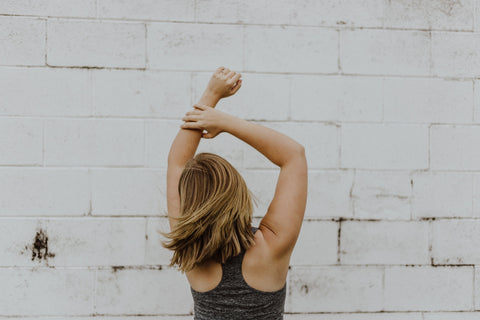woman wearing gray tank top doing tricep stretch