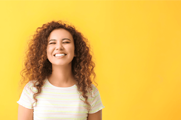 Woman smiling on bright yellow background