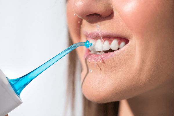 Lady using oral irrigator on teeth