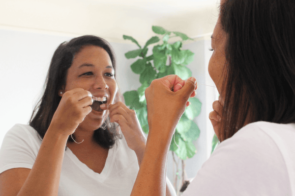 Woman flossing with MABLE Silk dental floss, compostable dental floss that is refillable