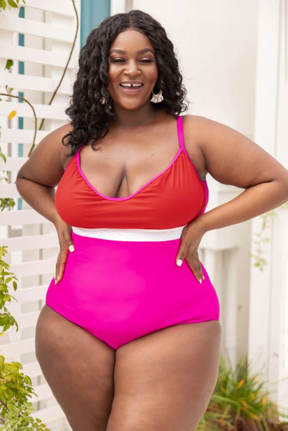 a smiling full figured woman modeling a caribbean crush swimsuit in pink