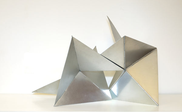 Shiny metal triangle sculpture on white background.