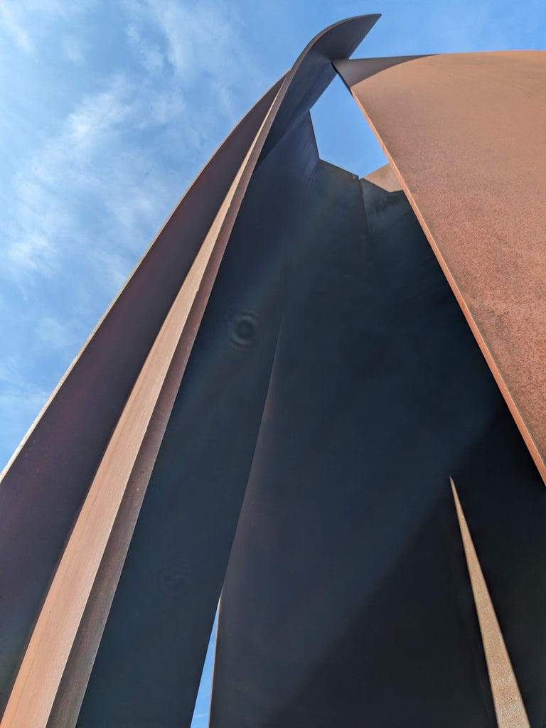 A large brown steel sculpture in front of a blue sky