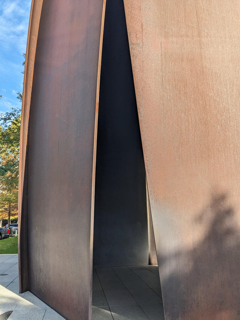 A large brown steel panel with a sliver of sky and trees showing on the left-hand side.