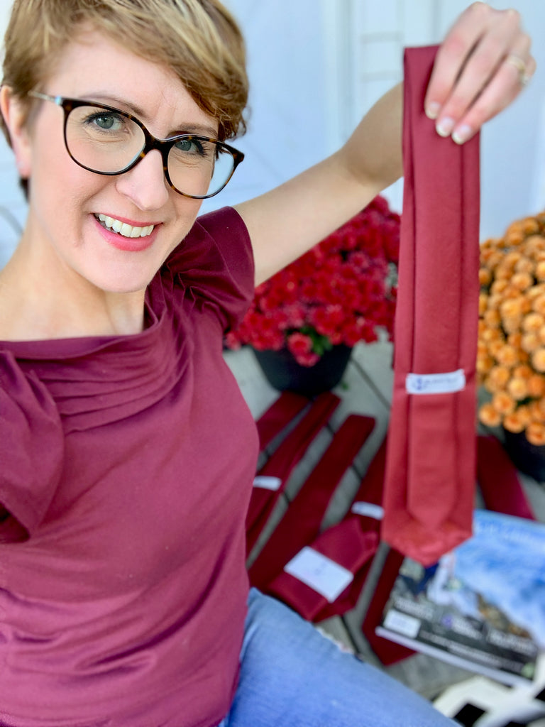 Laura Michaud holding burgundy necktie that she designed