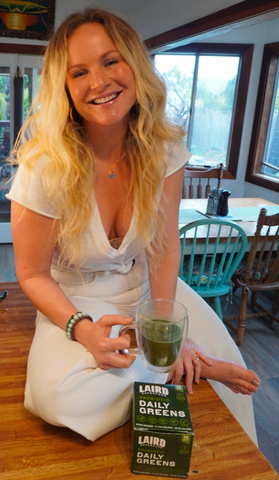 Bo Stanley Pro Surfer drinking Laird Superfood Prebiotic Daily Greens in a glass in her home
