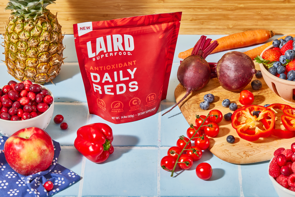 Laird Superfoods Daily Reds powder with healthy, vibrant and colorful real ingredients displayed on a countertop