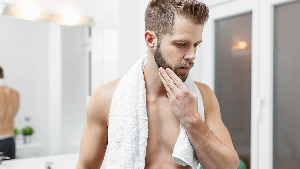 Man in bathroom after applying beard oil post shower