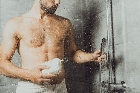 Bearded man in the shower using a beard care product to exfoliate