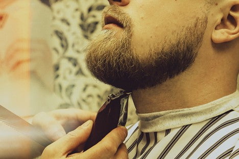 Bearded man getting a trim with electric clippers