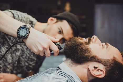 Man with long beard growth getting a trim in a barber chair