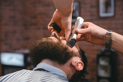 Bearded man getting his cheeks trimmed by a high quality trimmer
