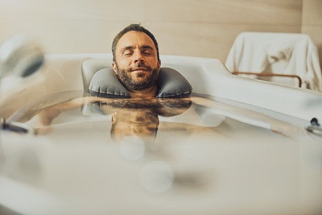Man relaxing in a bath tub while cleaning his beard