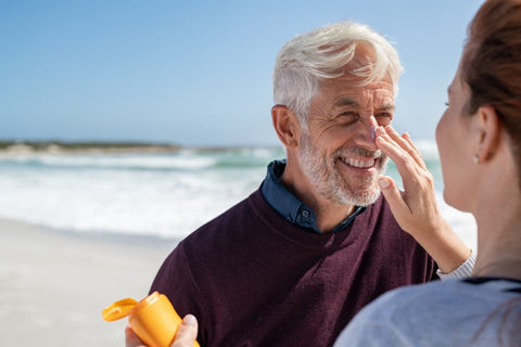 Woman applying sunscreen to the face of a bearded man