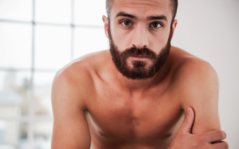 Bearded man looking in mirror after using beard oil for growth