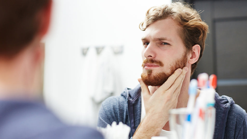 Man looking in mirror after using beard balm