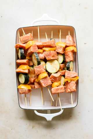 Salmon skewers made up and sitting in square dish