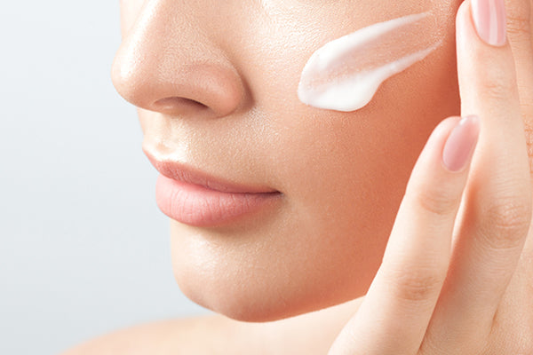 Close up of woman putting moisturizer on face.