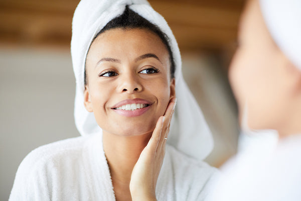 Head and shoulders portrait of smiling woman looking in mirror during morning routine.