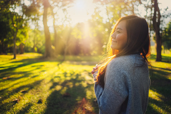 Woman standing among nature in the park before sunset.