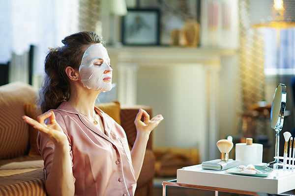 Relaxed woman with facial mask meditating.
