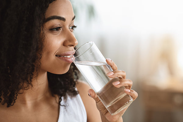 Smiling Woman Drinking Water From Glass And Looking Away.