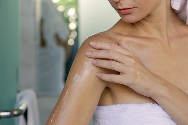 Woman applying moisturizer after shower.