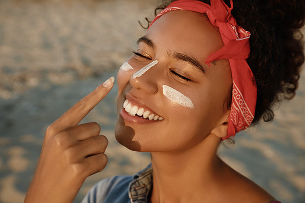 Woman putting sunscreen on her face.