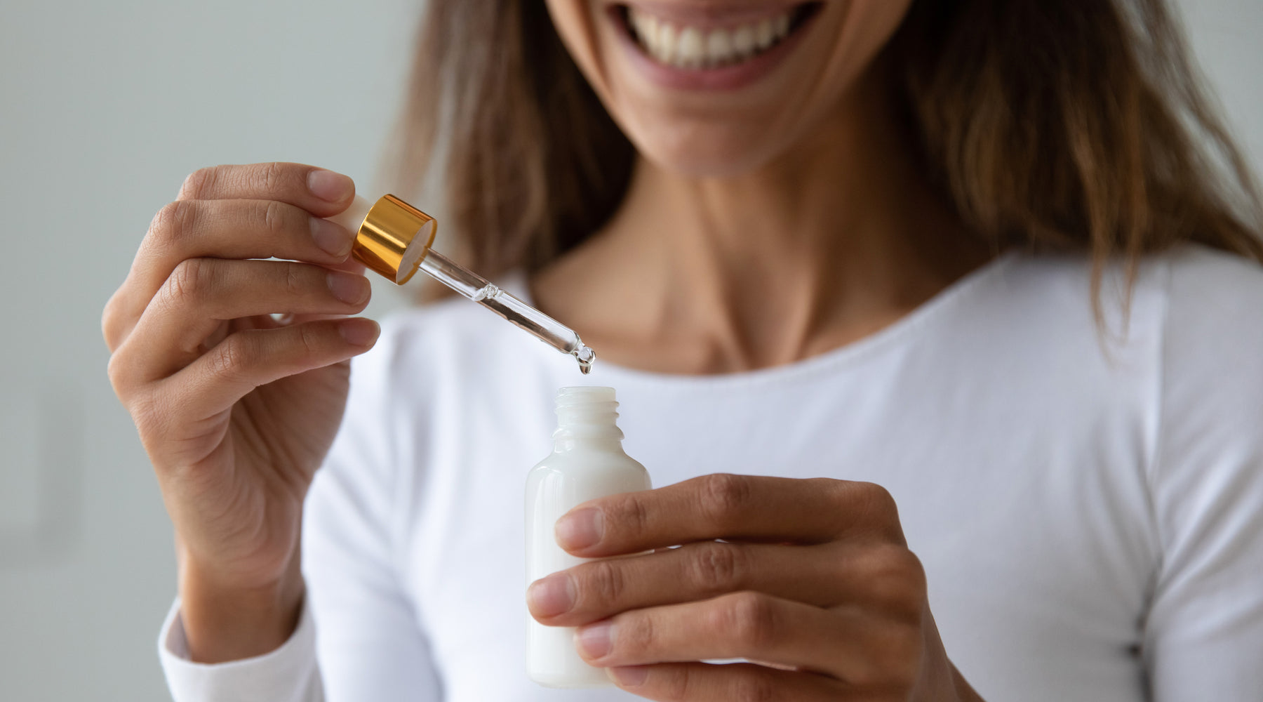 Woman taking face serum out of a bottle