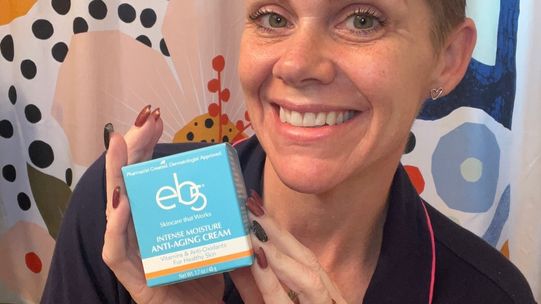 Woman smiling and moisturizing with eb5 Intense Moisture Anti-Aging Cream to reduce smile lines.