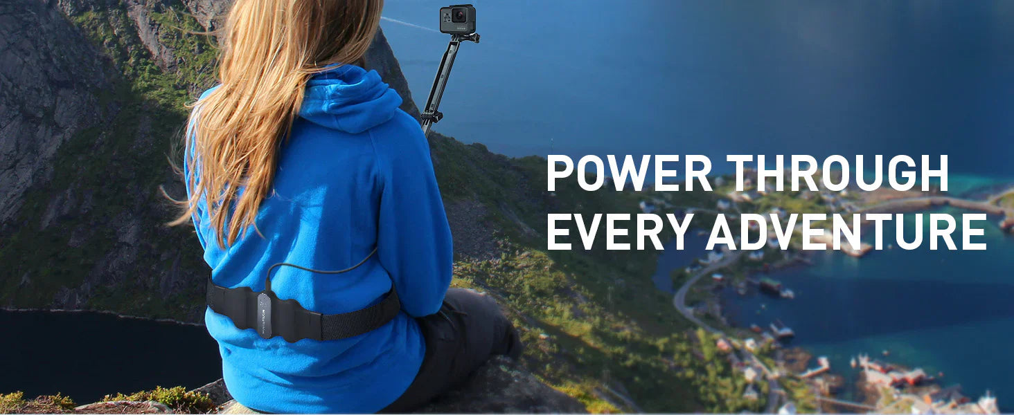 woman on top of a mountain holding a GoPro and wearing a VR battery pack for Quest 3 on her waist